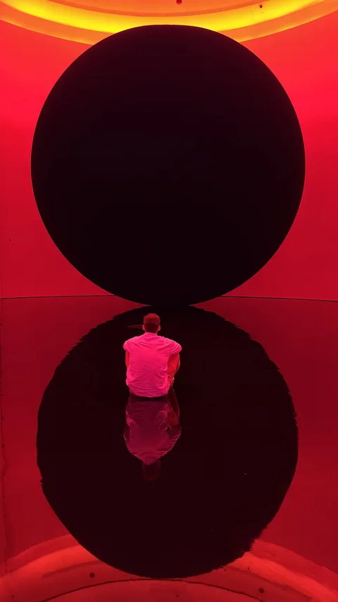 Luca osserva una grande installazione circolare illuminata di rosso